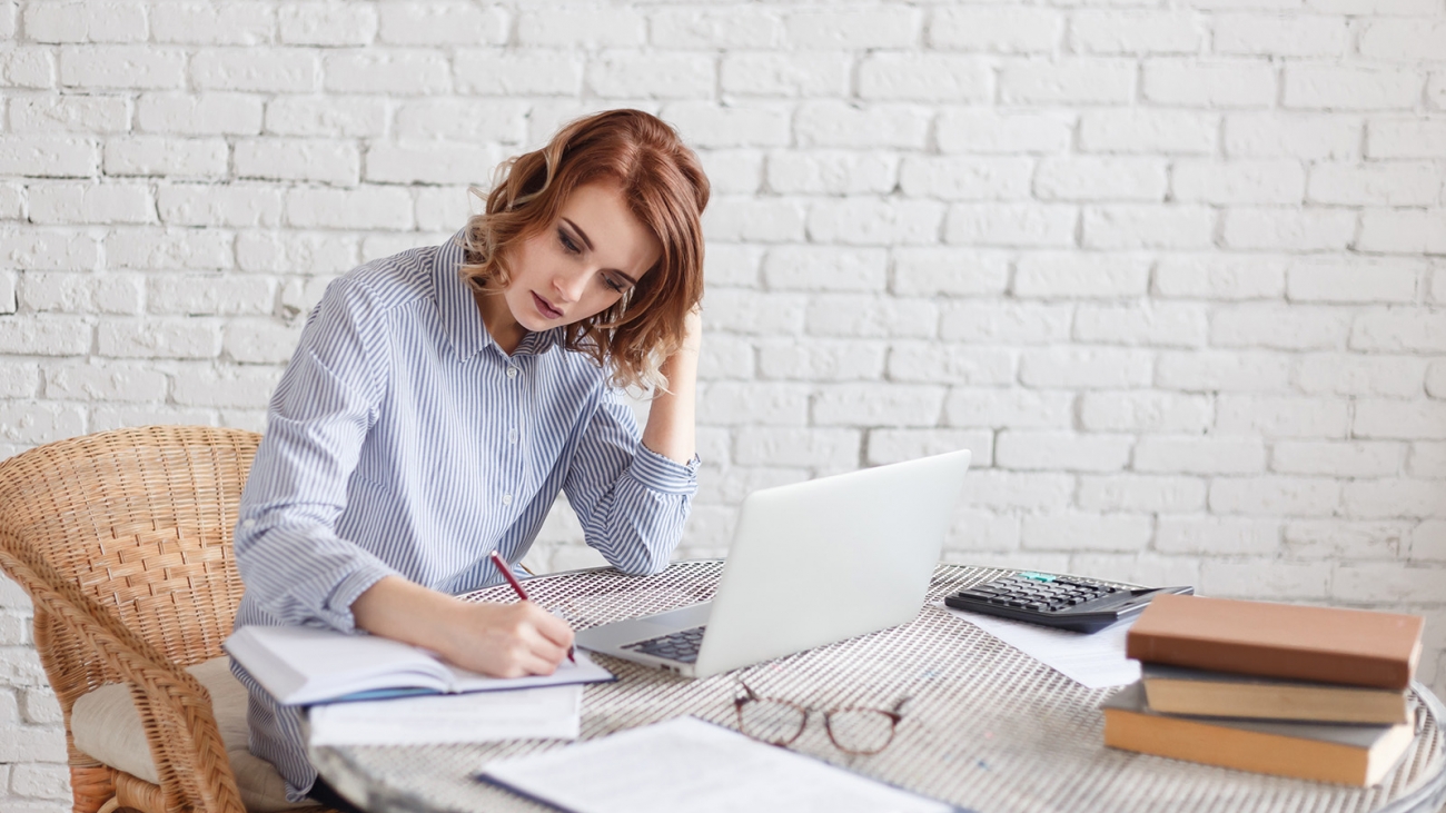 Woman freelancer female hands with pen writing on notebook at home or office.